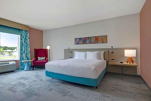 een slaapkamer met een groot bed en een rode stoel bij Hilton Garden Inn in Manassas