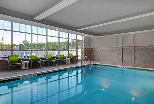 een zwembad met groene stoelen en een groot raam bij Hilton Garden Inn in Manassas