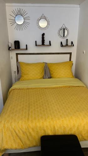 une chambre avec un lit jaune avec deux miroirs au mur dans l'établissement Adorable studio 20m2, à Aubervilliers