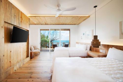 a hotel room with two beds and a flat screen tv at Ibagari Boutique Hotel in Roatan