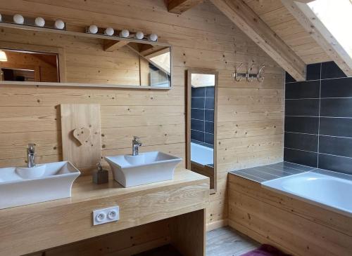 La salle de bains en bois est pourvue de 2 lavabos et d'une baignoire. dans l'établissement Chalet de Luxe Spacieux -12 pers- Sauna & Jacuzzi, à Xonrupt-Longemer