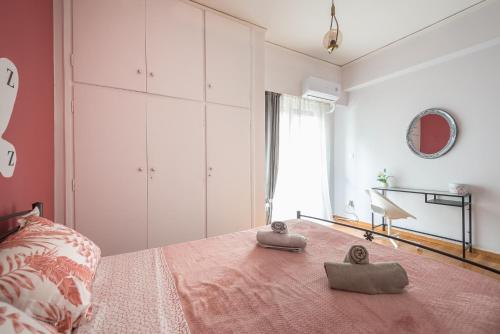 Schlafzimmer mit einem Bett mit rosa Tagesdecke in der Unterkunft Beautiful apartment, next to metro. in Athen