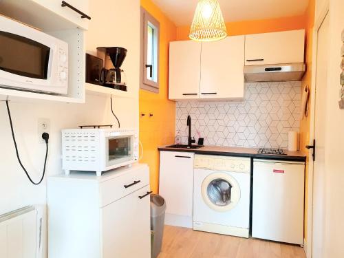 une cuisine avec des armoires blanches et une laveuse et une sécheuse dans l'établissement Charmant studio vue montagne, à Digne-Les-Bains