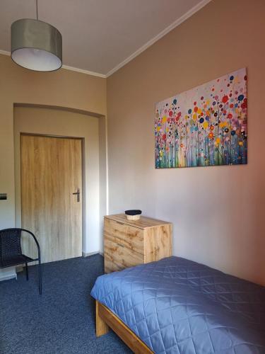 1 dormitorio con 1 cama y una pintura en la pared en Za zieloną bramą, en Zawiercie