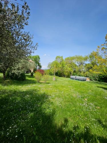 un champ d'herbe verte avec des arbres et un bâtiment dans l'établissement Le temps d'une pause ! Petit-déjeuner inclus !, à Servas