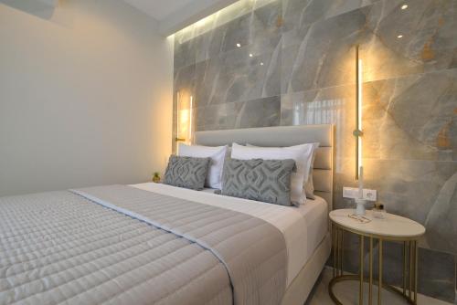a bedroom with a white bed with a stone wall at Irida Apartments in Leptokaria