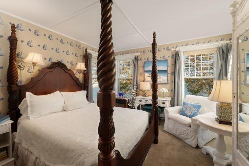 a bedroom with a bed and a chair and windows at Harbor Knoll Bed and Breakfast in Greenport