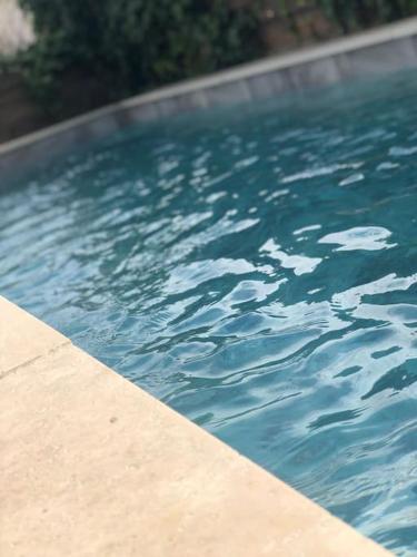 une piscine avec de l'eau bleue dans une cour dans l'établissement Maison provençale avec piscine, à Roquemaure