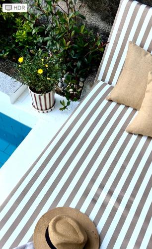 a hat sitting on a striped bench with plants at D'Oliva Gerês - River Side Houses in Geres