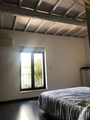 une chambre avec un lit et une fenêtre dans l'établissement Maison provençale avec piscine, à Roquemaure