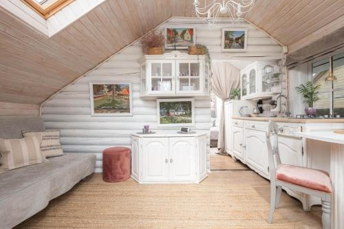 uma cozinha com armários brancos e um sofá num quarto em Guesthouse Delisa em Pärnu