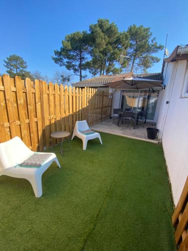 une cour avec des chaises, un parasol et une clôture dans l'établissement Bienvenue Chez Timta, à Arès