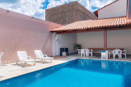 a swimming pool with chairs and a table and a building at Pousada Meia Lua in Pirenópolis