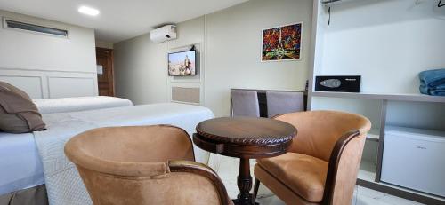 a room with a bed and two chairs and a table at Antonio's Hotel e Spa - Airport in Brasilia