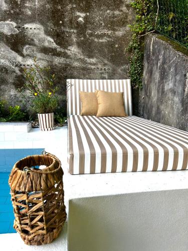 a striped couch sitting on a patio next to a basket at D'Oliva Gerês - River Side Houses in Geres