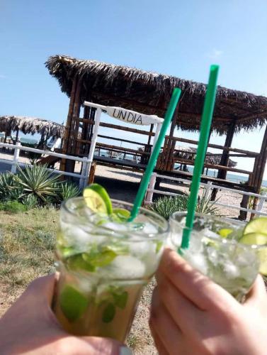 a person holding two drinks with green straws at Un Dia Boutique Resort in Playas