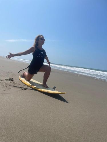 a woman on a surfboard on the beach at Un Dia Boutique Resort in Playas