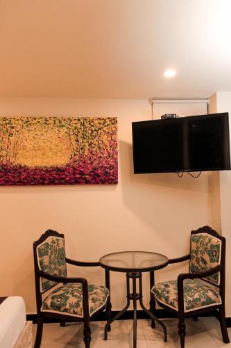 a room with a table and two chairs and a tv at Hotel Plaza Garibaldi in Caldas