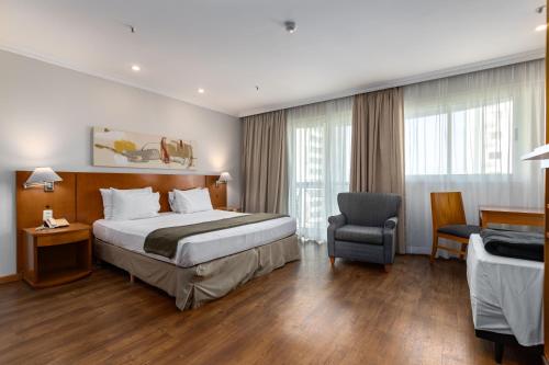 una camera d'albergo con letto e sedia di Lobie Barra da Tijuca Mundo Novo a Rio de Janeiro