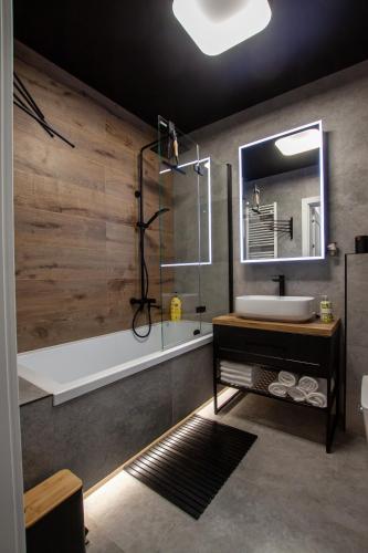 a bathroom with a tub and a sink and a mirror at Apartament Na Stoku Kielce in Kielce