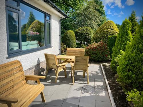 a patio with a wooden table and chairs and bushes at 3-bedroom bungalow, central Ambleside with parking in Ambleside