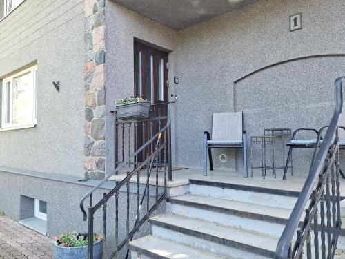 a porch with stairs leading to a door with a chair at Kraavi Guest Hostel in Kuressaare