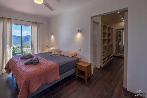 a bedroom with a large bed and a large window at Villa Cap Sud avec piscine et vue mer in Les Anses-dʼArlets