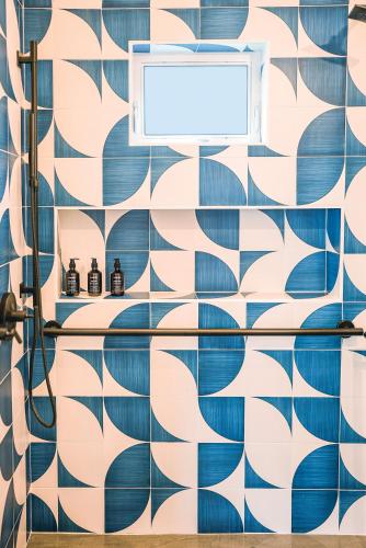 Funboard Room includes King Bed and Mini Kitchenette في شاطئ ستينسون: حمام به جدار من البلاط الأزرق والأبيض