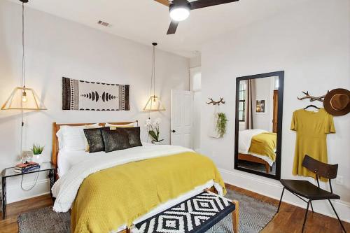 a bedroom with a bed with a yellow blanket and a mirror at Designer Home Walking Distance To The French Quarter's in New Orleans