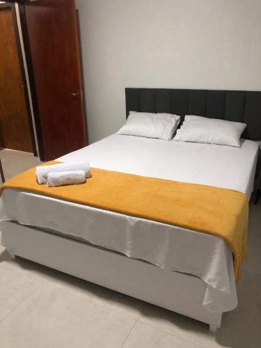 a bed with two towels sitting on top of it at Quarto privativo 01 in Sinop
