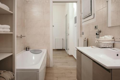 Baño blanco con lavabo y bañera en Appartamento Al Borgo, en Bienno