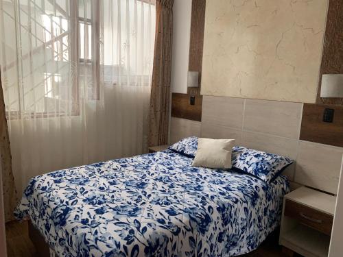 a bedroom with a blue and white bed with a window at Depa A-Primer Piso in Cajamarca