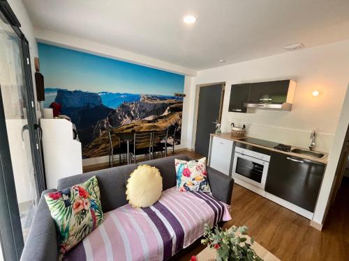 un salon avec un canapé et une cuisine dans l'établissement L'escapade dauphinoise, gîte 2 chambres avec terrasse et clim, à Beaucroissant