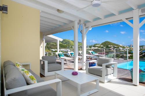 eine Terrasse mit Stühlen, einem Tisch und einem Pool in der Unterkunft Villa Eskarcel, vue mer sur Orient Bay, piscine chauffée, très spacieuse in Cul de Sac