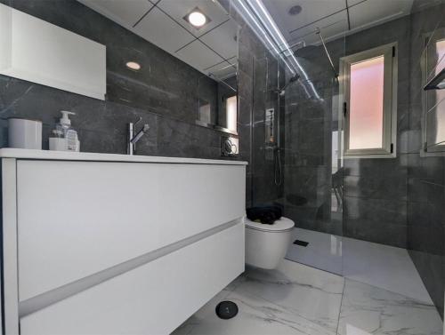 a bathroom with a white sink and a toilet at Fee4Me 2 Bedroom House with Private Pool and Rooftop Terrace in Alicante