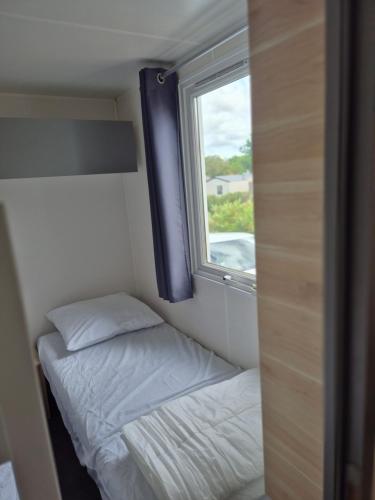 une petite chambre avec un lit et une fenêtre dans l'établissement Camping 4 etoiles les viviers lege cap ferret, à Lège-Cap-Ferret