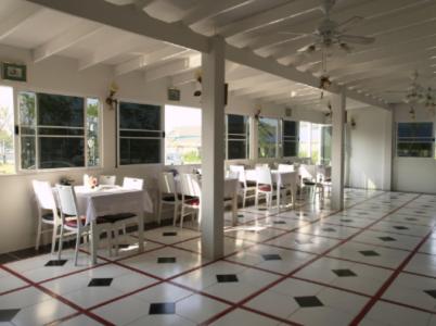 uma sala de jantar com mesas brancas e cadeiras brancas em Chomdao Hotel em Rayong
