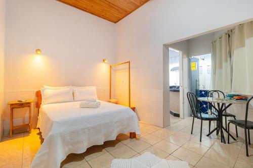 - une chambre avec un lit blanc et une table dans l'établissement Pousada Meia Lua, à Pirenópolis