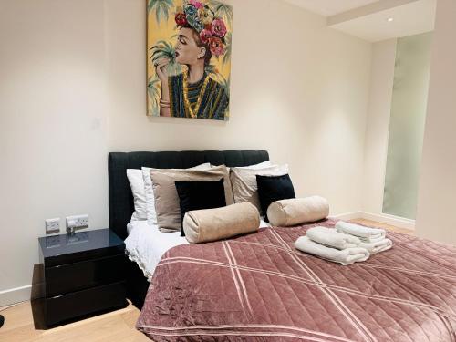 a bedroom with a bed with a painting on the wall at Apartments next to the O2 Arena 10 in London