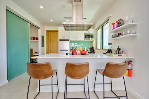 a kitchen with a large white island with two bar stools at Luxury Condo at Harbour Walk in Red Bay Estate