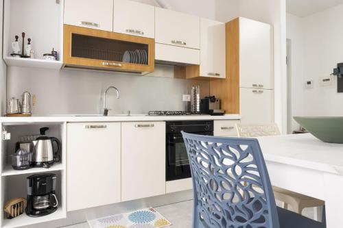 a kitchen with white cabinets and a blue chair at Appartamento Clalia in Luino