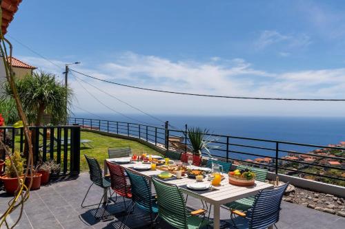 a table with food on top of a balcony with the ocean at Casa das Maravilhas by An Island Apart in Câmara de Lobos