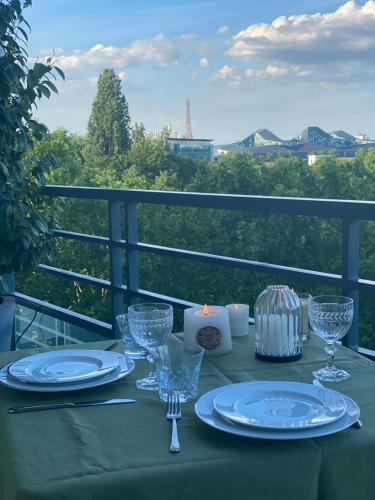 a table with plates and wine glasses on a balcony at Vue sur Tour Eiffel in Issy-les-Moulineaux