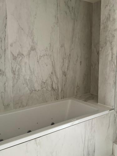 a white bath tub in a bathroom with marble walls at Vue sur Tour Eiffel in Issy-les-Moulineaux