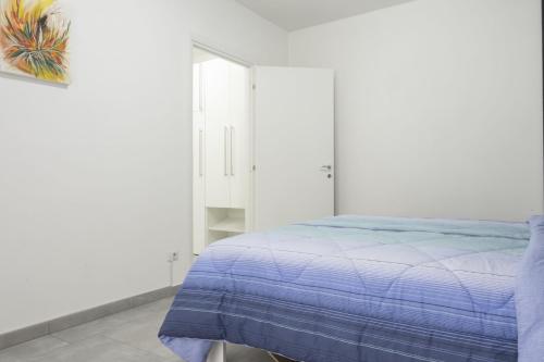 a white bedroom with a bed with a blue blanket at Appartamento Clalia in Luino