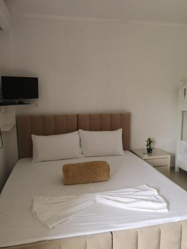 uma cama com lençóis brancos e uma almofada castanha em Guest House Emi em Berati