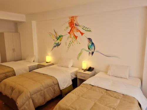 a room with three beds and a painting of birds on the wall at HOTEL AEROPUERTO Cusco in Cusco