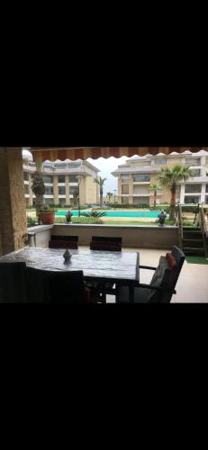 a room with a table and chairs and a building at Location prestigia plage des nations in Sidi Bouqnadel
