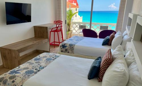two beds in a room with a view of the ocean at Beach and Ocean Front Apartments Cancun in Cancún