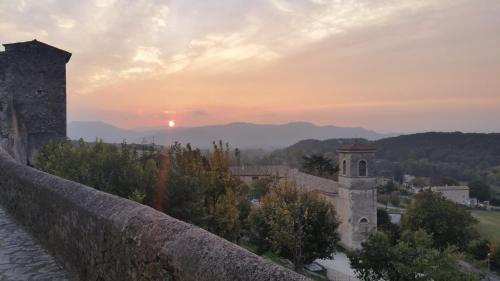 um pôr-do-sol sobre uma parede de pedra com um edifício e uma torre em La Capitelle em Mirmande